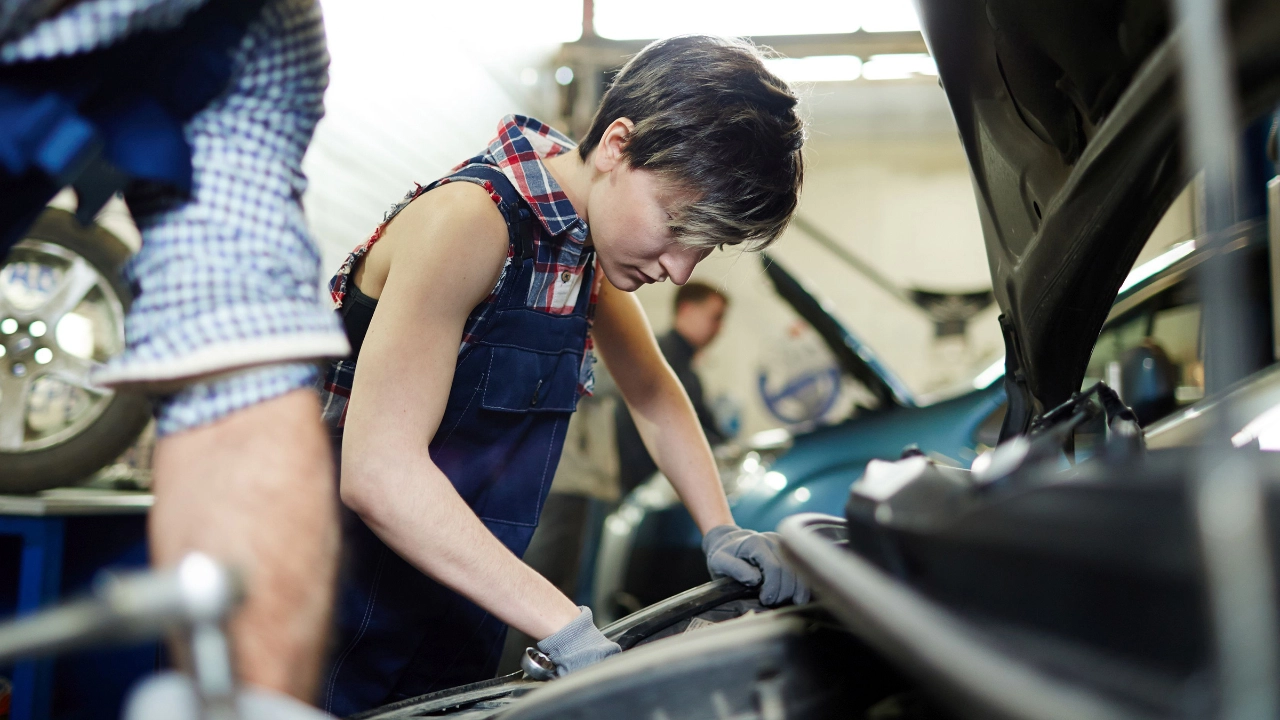 Eine Mechanikerin schraubt an einem Auto