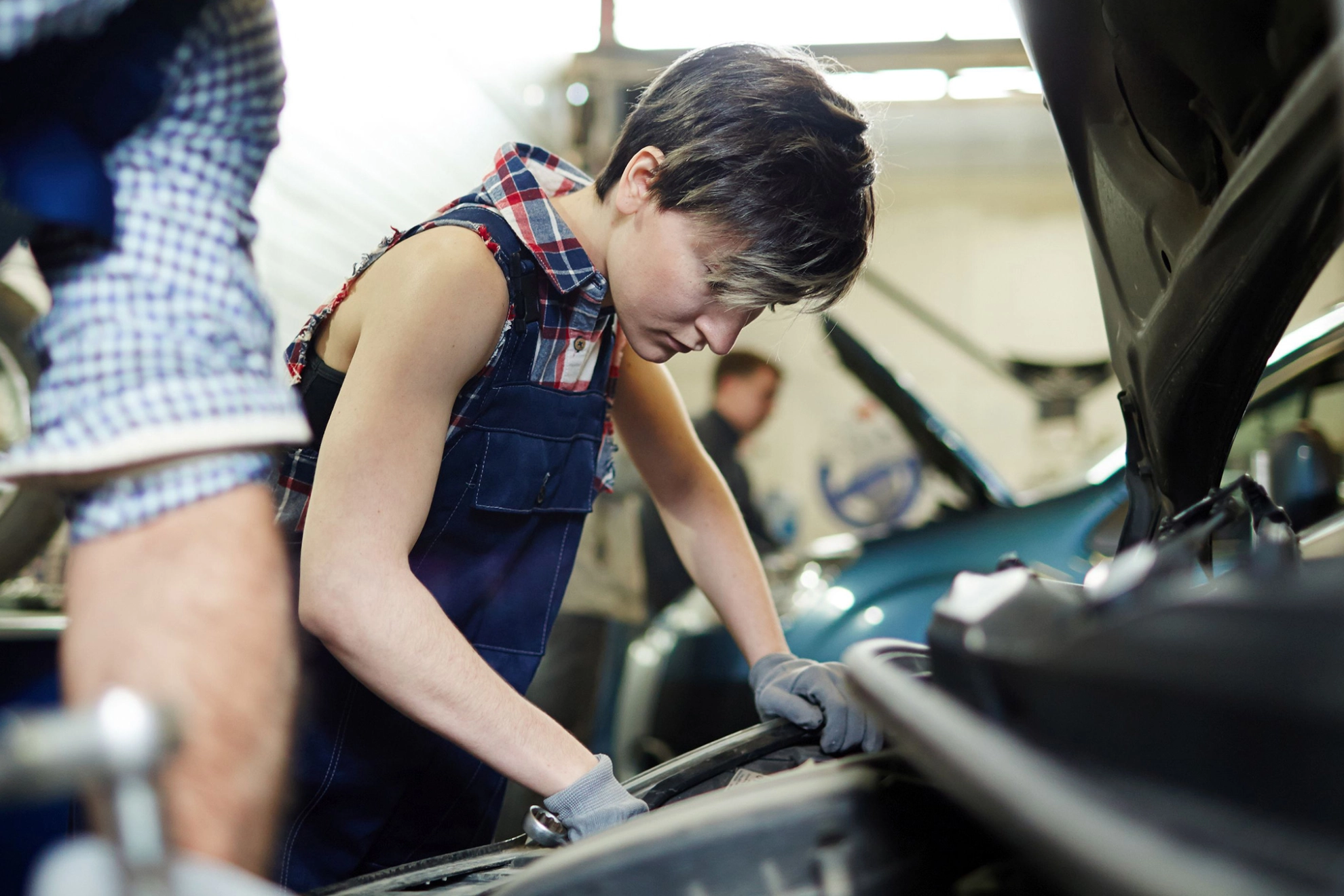 Eine Mechanikerin schraubt an einem Auto