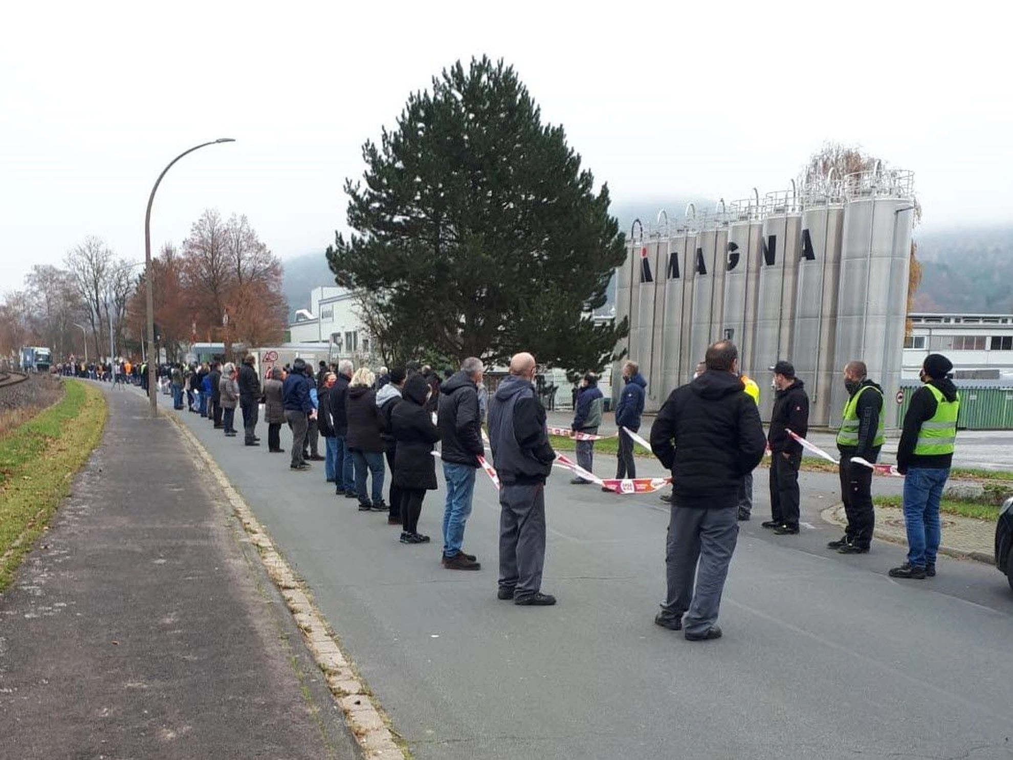 Beschäftigte bilden eine Menschenkette vor ihrem Betrieb Magna Mirrors in Dorfprozelten.