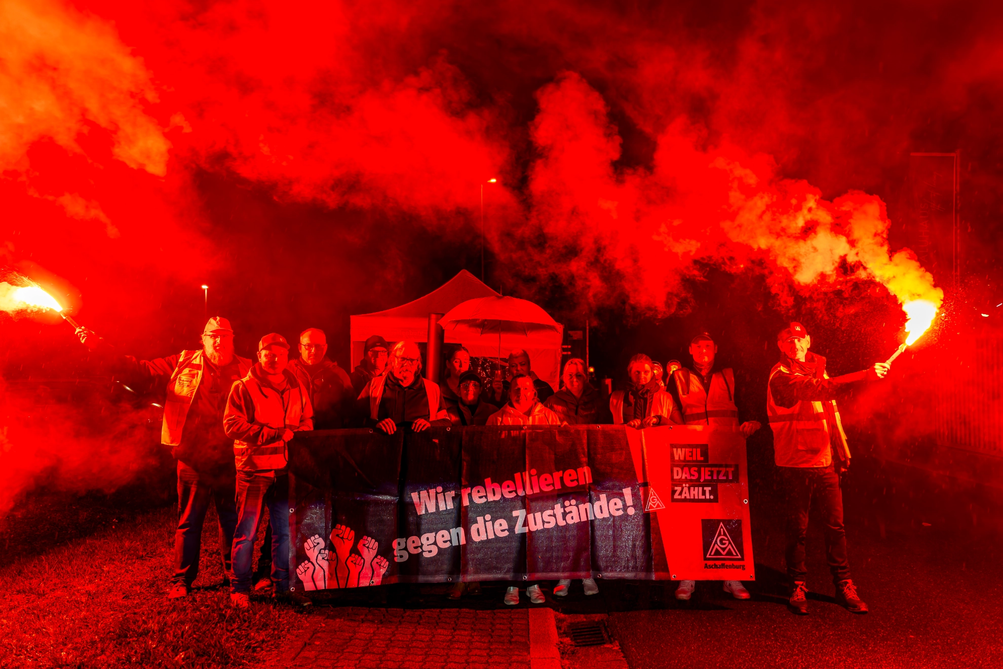 Beschäftigte von Magna eröffnen mit roten Bengalos am 23.10.2026 ihre Mahnwache vor dem Werk in Dorfprozelten