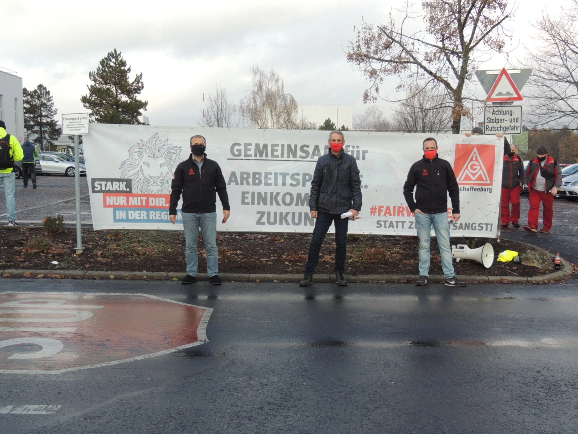 Das Bild zeigt Öczan Pancarci, Percy Scheidler und Manuel Leiderer vor einem Banner "Gemeinsam für Arbeitsplätze. Einkommen. Zukunft."
