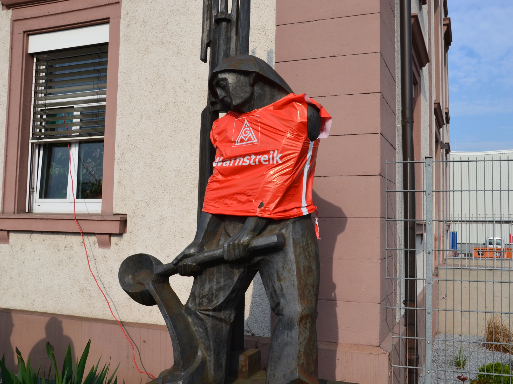 Das Rexroth-Wahrzeichen "Der Eisengießer" vor der alten Hauptpforte in Lohr mit einer Warnstreikweste